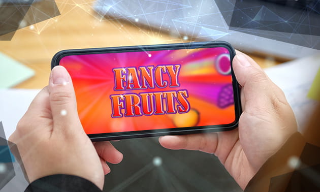 Der Schriftzug von Fancy Fruits auf einem Smartphone, das in Händen gehalten wird.
