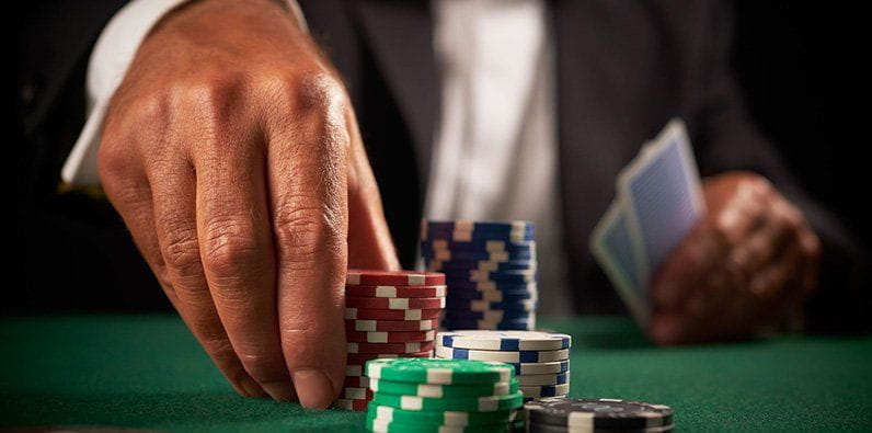 Mann setzt Chips an einem Pokertisch